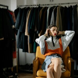 A stylish female model sits in a retro wardrobe setup.
