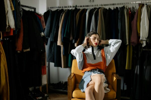 A stylish female model sits in a retro wardrobe setup.