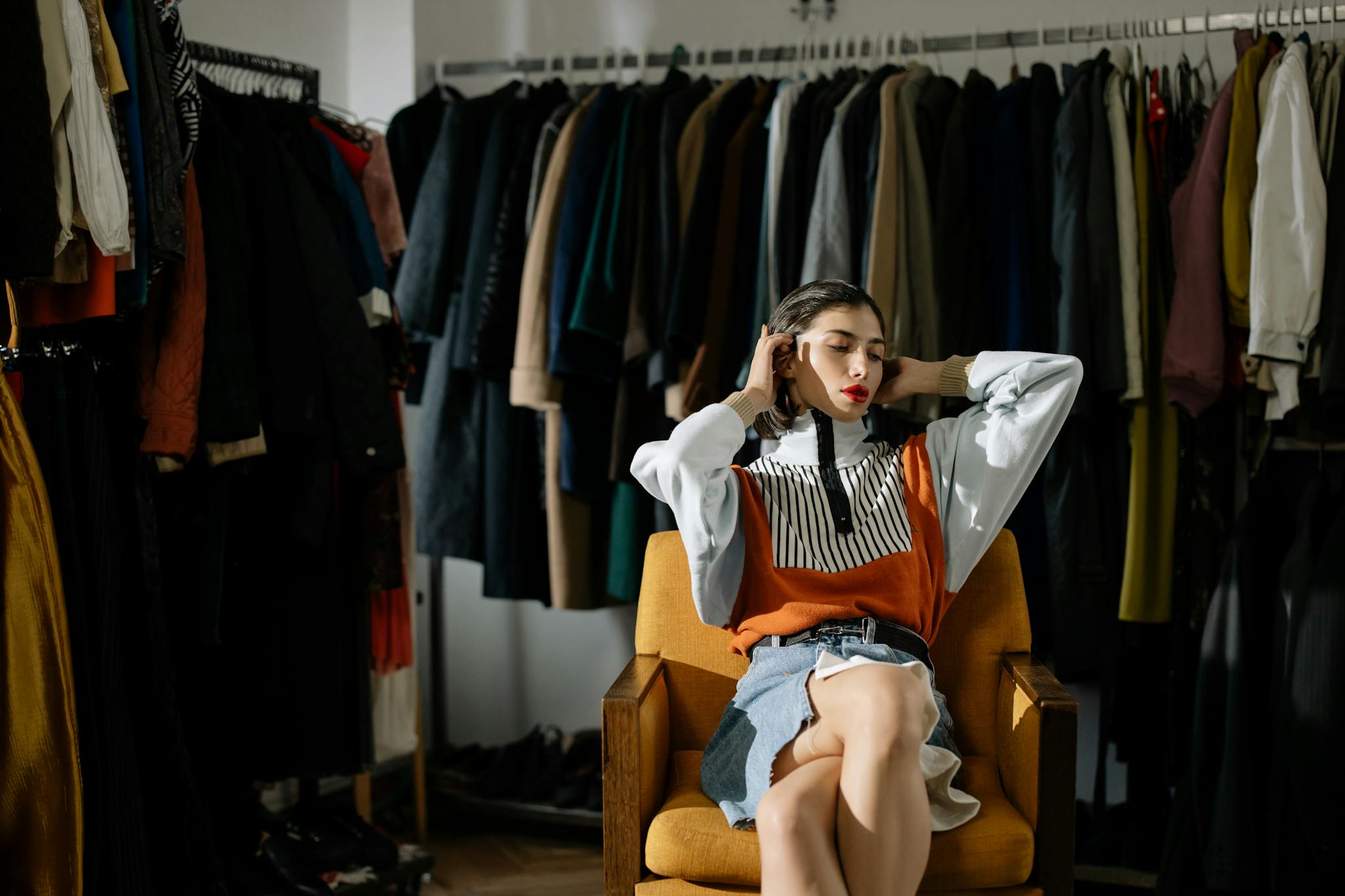 A stylish female model sits in a retro wardrobe setup.