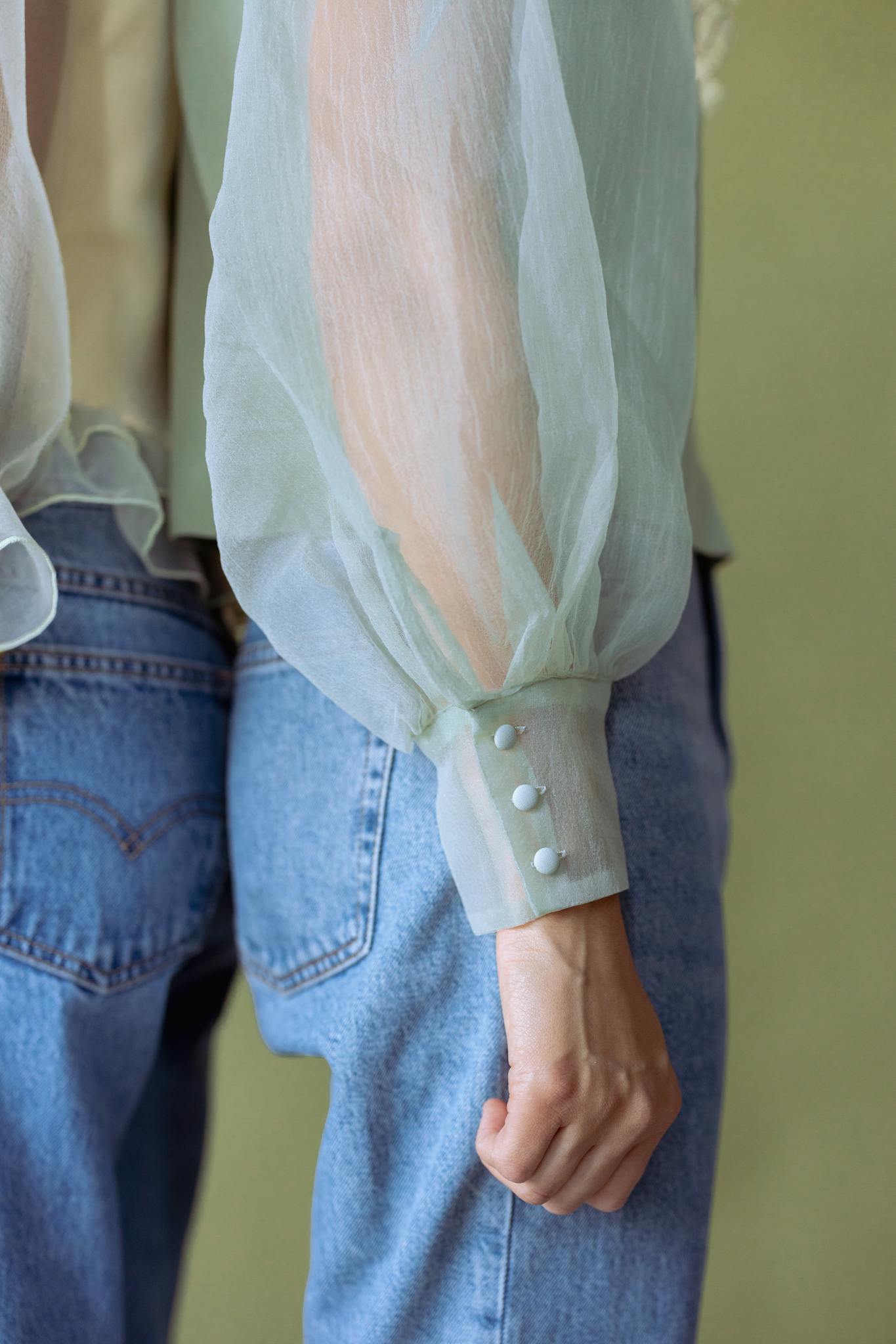 Close-up of a stylish chiffon blouse paired with blue jeans, showcasing modern casual fashion.